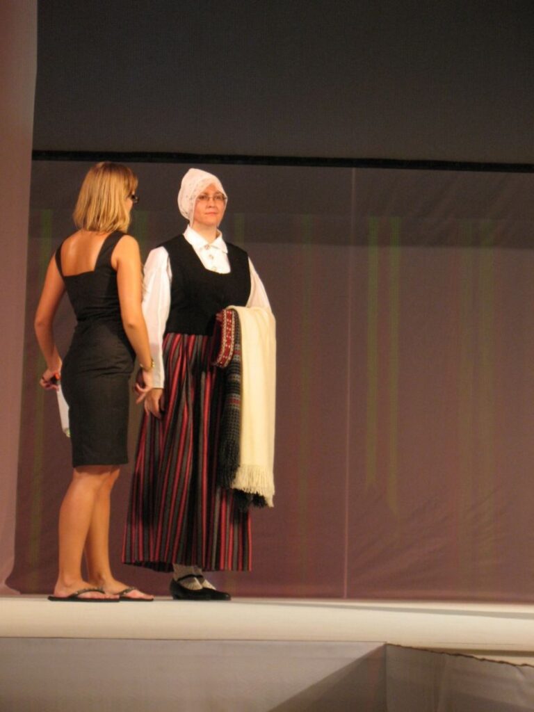 Smilteniete Dita Brūzīte savu pašdarināto Launkalnes tautas tērpu skatē pati arī demonstrēja, ejot pa “mēli”. Attēlā – uzklausot skates režisora asistentes padomus.
Autors: No personīgā arhīva