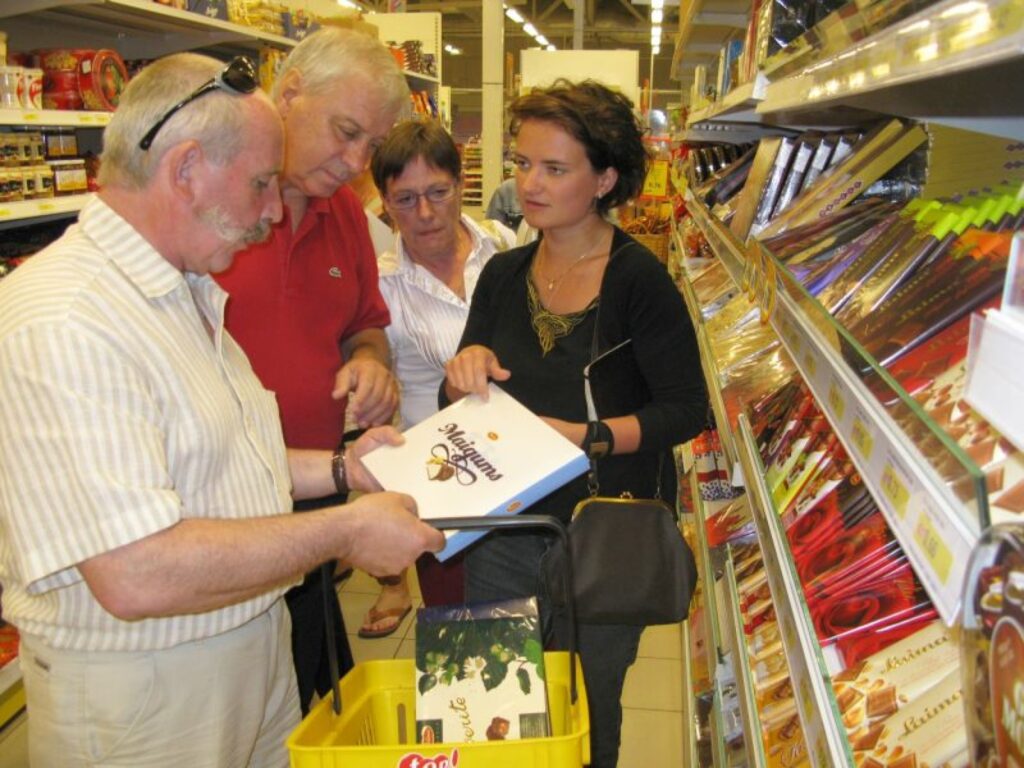 Pirmais, kas veikala plauktos interesēja frančus, bija Latvijā ražotā šokolāde. To Etjēnam Burgeram (no kreisās), Žanam Danielam Zeteram un Elizabetei Burgerei palīdz izvēlēties sadarbības koordinatore Dace Resele.
Autors: Sandra Pētersone