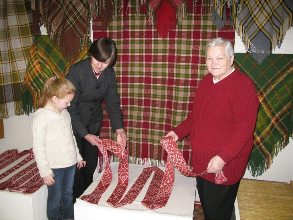 Pirmklasniecei Montai Līgai Mītniecei tautas daiļamata meistares Raitas Leites (no kreisās) izstādē patīk viss. “Es jau nemāku aust, bet man patīk, kā citi taisa darbus,” meitene stāsta studijas “Smiltene” vadītājai Inesei Kauliņai. 
Autors: Sandra Pētersone