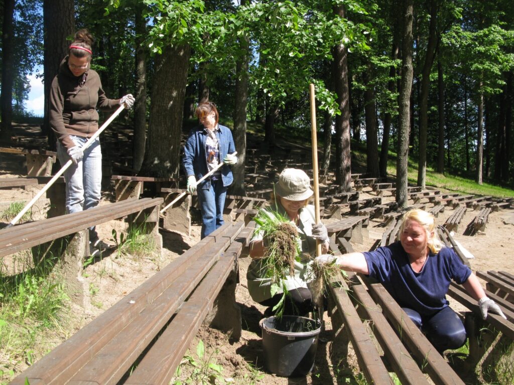Jāņukalna estrādē  simts latu stipendiātes ravējot jūtas gandrīz kā biešu vagās. Starp soliņiem izaugusi tik gara zāle, ka dažviet stiebri jau spraucas cauri solu virsmām. 
Autors: Sandra Pētersone