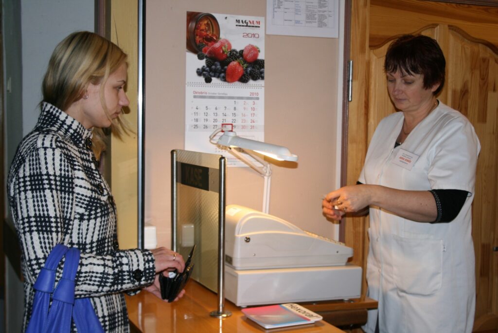 Smiltenes poliklīnikas reģistratorei Andai Rimšai (no labās) ne reti nākas skaidrot pacientiem, ka uz vairākiem valsts finansētiem izmeklējumiem ir jāgaida rindā. Smilteniete Marika Fjodorova nevar atļauties maksas pakalpojumu, lai rindu apietu. 
Autors: Sandra Pētersone