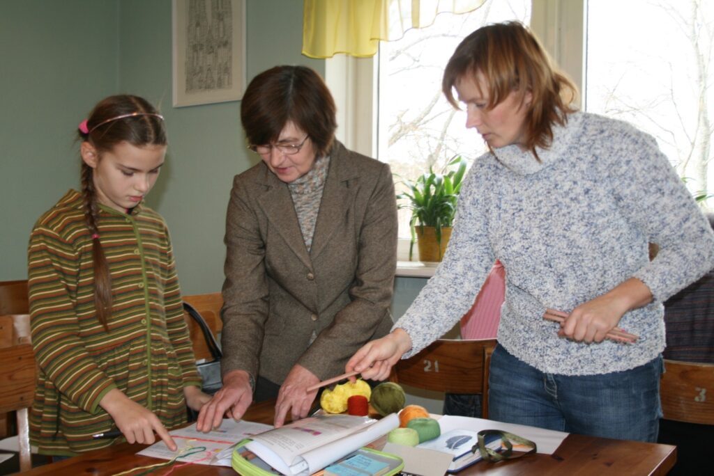  Aušanas meistare Inese Kauliņa (vidū) palīdz izvēlēties prievītes rakstu un krāsas grundzālietei Elzai Ķesterei un viņas mammai Ingai. Elza mudināja mammu apmeklēt Tradicionālo prasmju skolu Smiltenē, lai iemācītos aust prievīti. 
Autors: Sandra Pētersone