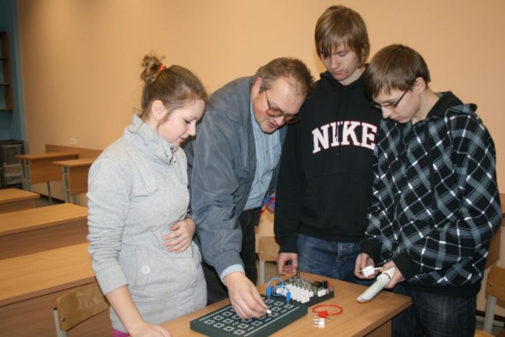 Valkas ģimnāzijas 9. klases skolēni Jānis Bērtiņš (pirmais no labās), Niks Kristians Bodnieks un Līga Lāce sava fizikas skolotāja konsultanta Valda Jeruma vadībā sākuši gatavoties sacensībām zināšanās ar konkurentiem citās skolās. 
Autors: Aivars Zilbers