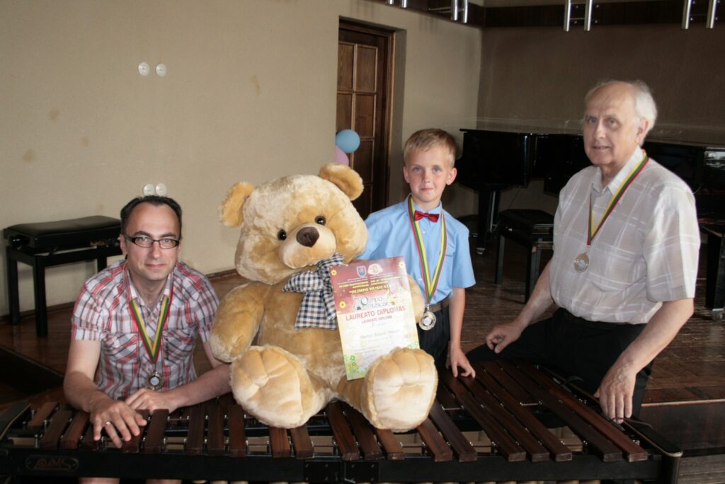Mārtiņš Rihards Mazurs (centrā) kā uzvarētājs saņēma lielu laimes lāci, diplomu un medaļu. Medaļas arī viņa pedagogam Guntim Freibergam un koncertmeistaram Andrim Niklavičam.
Autors: Aldis Dubļāns