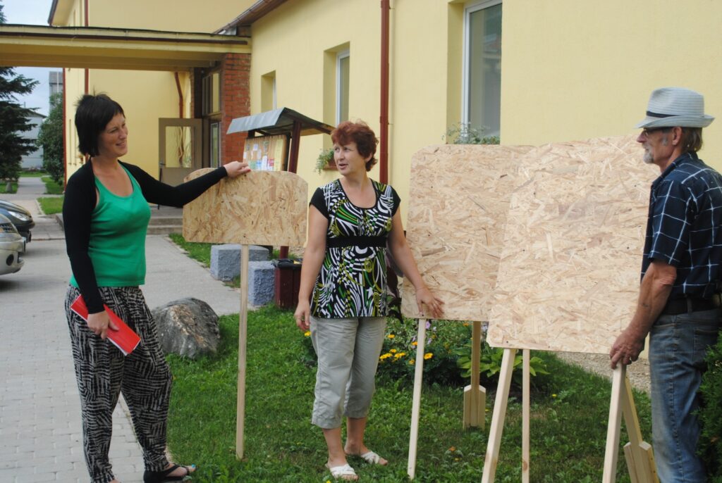 Palsmanieša Andreja Tammes (no labās) darinātajiem novada svētku informatīvajiem stendiem labāko vietu izvēlas kultūras nama vadītāja Aija Zeibote (no kreisās) un bibliotekāre Vingra Bērtiņa. 
Autors: Sandra Pētersone