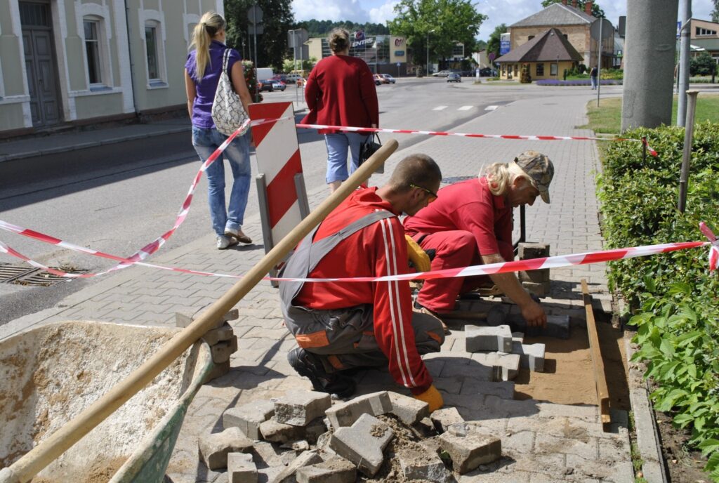 Iespējams, ūdens izskalojis smiltis, un tāpēc bruģis krīt iekšā, spriež strādnieks Raitis Suliņš, labojot ietves bruģi pie pasta ēkas.
Autors: Sandra Pētersone