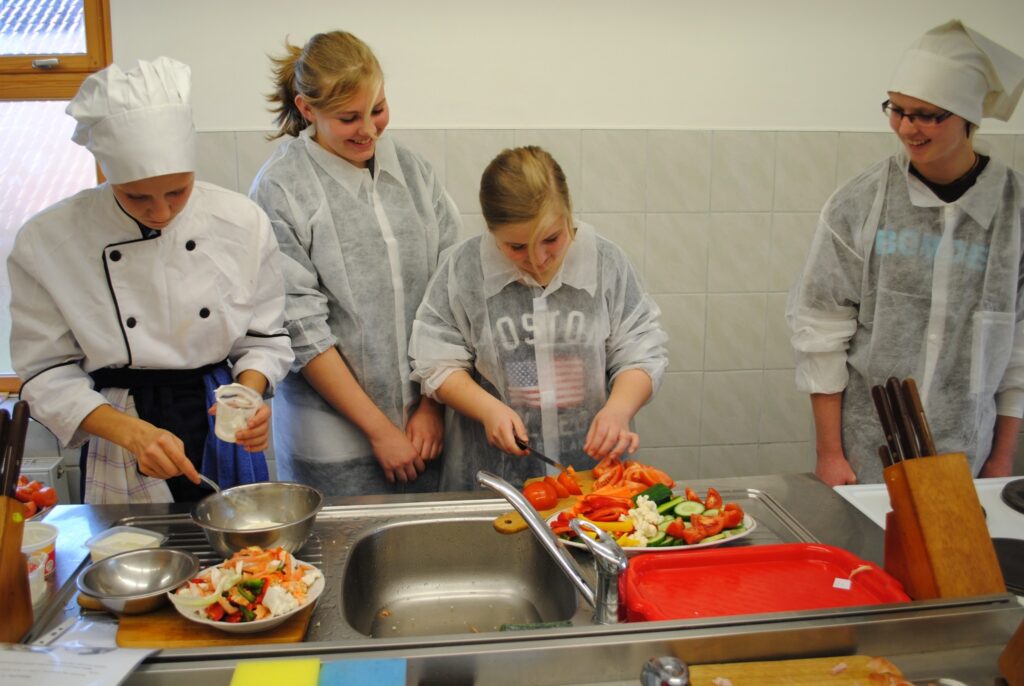 Arī Latvijā novērtē veselīgu uzturu, secina jaunietes no Norvēģijas, ciemojoties Centra vidusskolā un tehnikumā, kur kopā ar Elīnu Seipuli (no kreisās) un citiem audzēkņiem gatavoja ēdienu piknikam. 
Autors: Sandra Pētersone