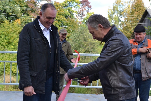 Blomes pagasta pārvaldes vadītājs Gaidis Bogdanovs (no kreisās) pietur sarkano lenti, lai būvdarbu vadītājs Guntis Paulsons (SIA “Ceļinieks 2010”) veiksmīgi to pārgrieztu. Atklāšanā neiztika bez laba vēlējumiem un humora. Izrādās tie, kuri dzīvojuši tilta tuvumā, teikuši, lai remontē ilgāk, jo pierasts pie klusuma. Savukārt tie iedzīvotāji, gar kuru mājām novirzīta satiksmes plūsma, ar nepacietību gaidījuši, kad atgriezīsies ierastā kārtība un klusums. 
Autors:  SANTA SINKA