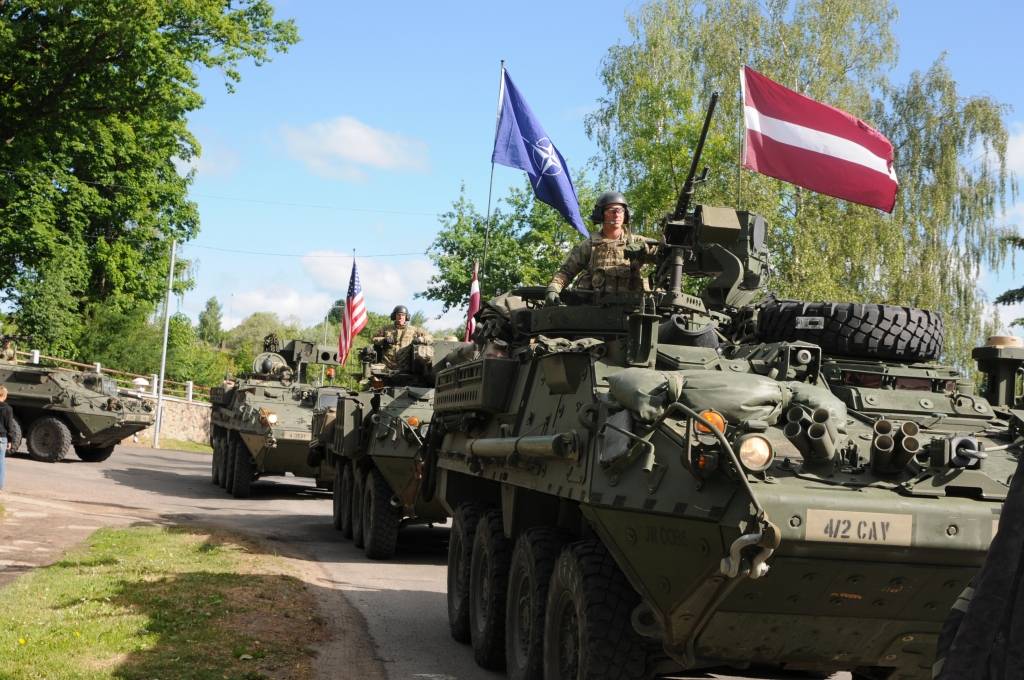 Virs ASV bruņumašīnām plīvo ASV, Latvijas un Igaunijas karogi. Triju valstu karavīri piedalīsies mācībās, stiprinot aizsardzības spējas.   