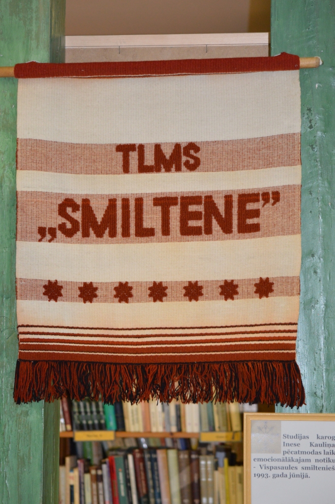 Izstādē bibliotēkā var apskatīt arī studijas karogu, ko audusi bijusī ilggadējā TLMS “Smiltene” vadītāja Inese Kauliņa, gatavojoties Vispasaules smilteniešu salidojumam 1993. gada jūnijā.
