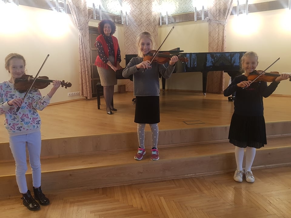 Jāņa Cimzes Valkas mūzikas skolas direktore, vijolnieku ansambļa vadītāja Līga Veinberga savas audzēknes – Doroteju Šutovu (no kreisās), Angelu Umaņecu un Violetu Miņjakovu – uzteic par cītīgu mācīšanos.