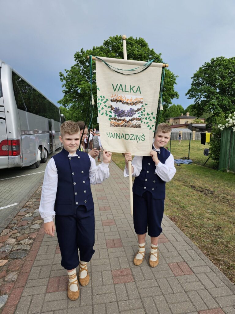 Brāļiem Dāvim un Miķelim tas gods nest kolektīva karogu.