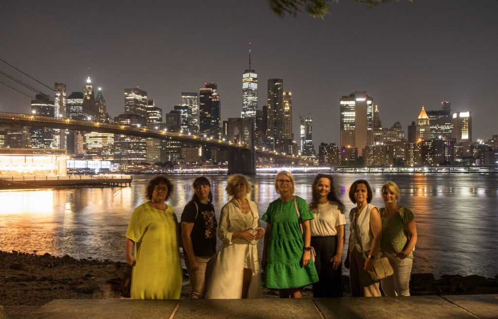 Ceļotāju kompānijai no Smiltenes daudz iespaidu atstājusi naksnīgā Ņujorka. Aiz dāmām fonā Bruklinas tilts, kas savieno Manhetenu un Bruklinu, šķērsojot Īstriveru.