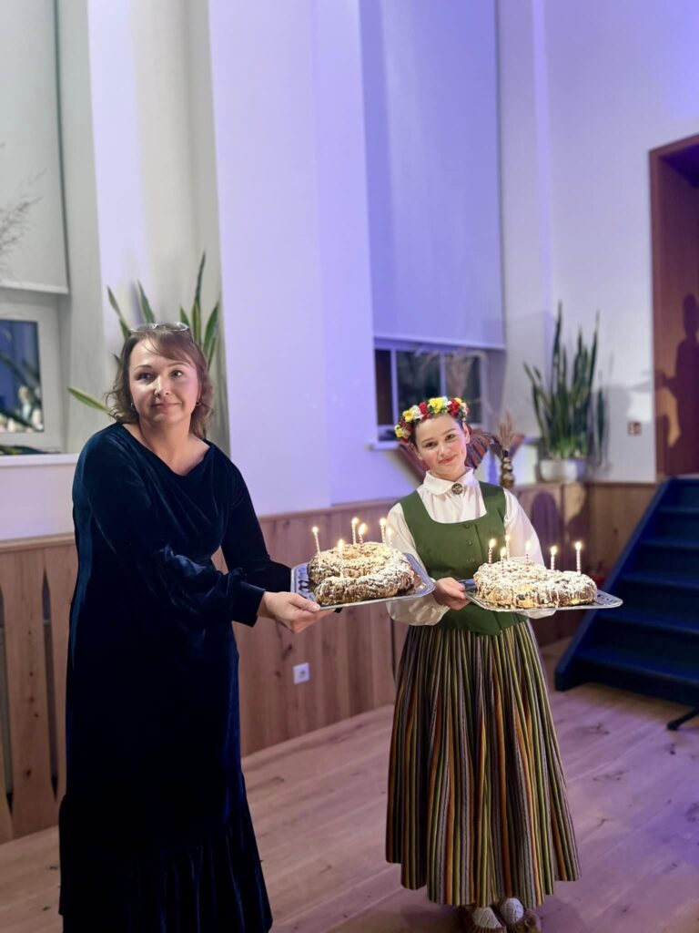 Par godu Apes dzimšanas dienai bija sarūpēts īpašs kliņģeris, ar cipariem – 96. Attēlā Apes apvienības pārvaldes vadītāja Liene Ābolkalne un Paula Nika Sīmane (tautisko deju kolektīvs “Nebēdnieki”).