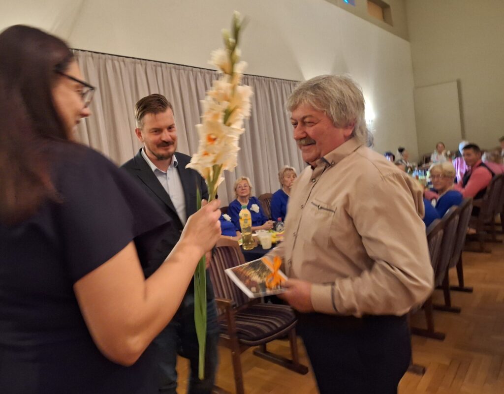 Vijciema bibliotēkas vadītāja Ilona Motuka un pagasta pārvaldes vadītājs Pēteris Pētersons sveic senioru, vijciemieti Andreju Kamoliņu, kuram šogad apritēja 65 gadi.