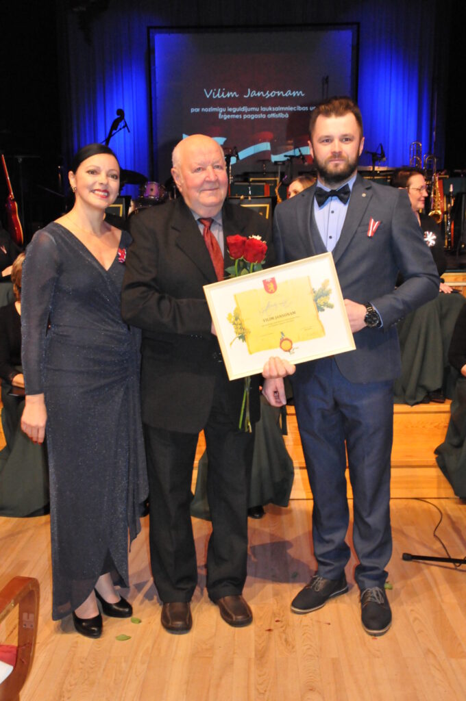 Lauksaimniecības zinību profesionālim Vilim Jansonam par mūža ieguldījumu apbalvojumu pasniedz pašvaldības vadītāja Gita Avote un mazdēls, priekšsēdētājas vietnieks Kristaps Sula.