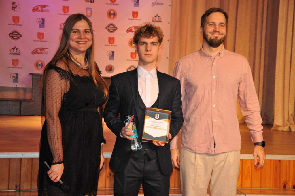 Inese Kāposte sveic cerīgāko futbola klases audzēkni Ņikitu Melančuku (vidū) un viņa treneri Raivi Graņicu.