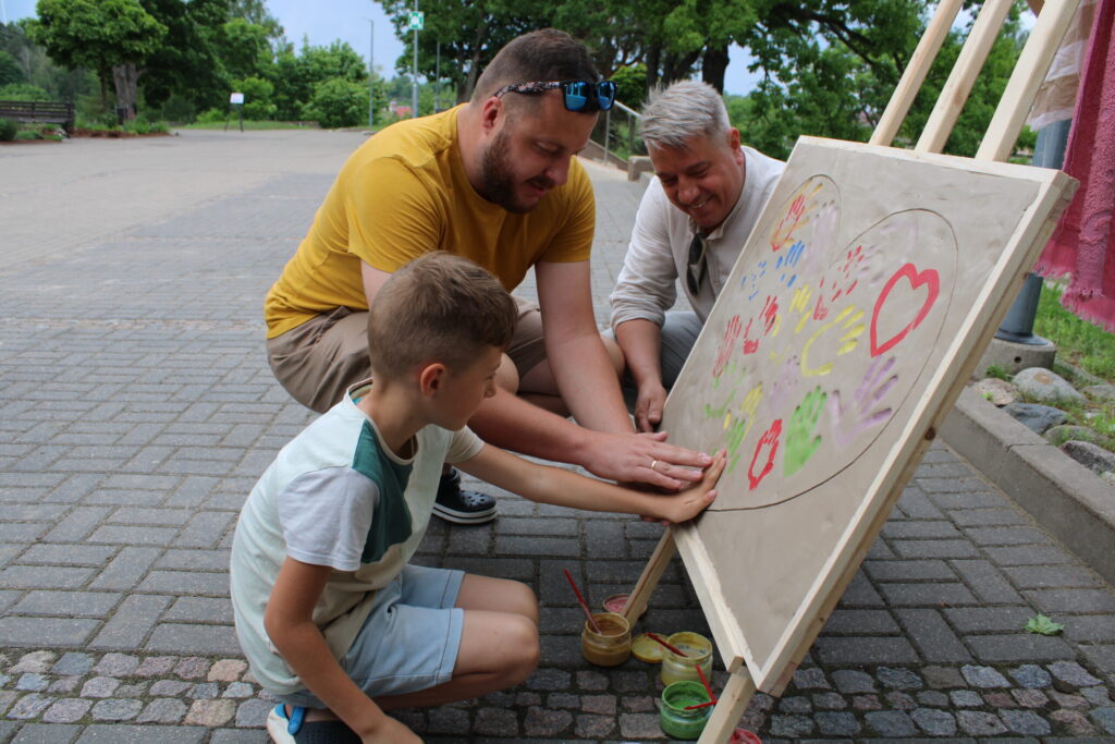 Specializētās darbnīcas “Kārkli” (Drustu pagasts) kopā ar labdarības pasākuma apmeklētājiem radīja paliekošu vērtību – akcijas “Balta, balta mana sirds” logo attēlojumu mālā, kas turpmāk ceļos līdzi visām akcijas norisēm, to reklamējot. Savas plaukstas nospiedumu tur atstāja arī smiltenietis Pauls, asistējot savam tētim Matīsam Mežulim (vidū) un “Kārklu” pakalpojumu vadītājam Aivaram Damrozem.