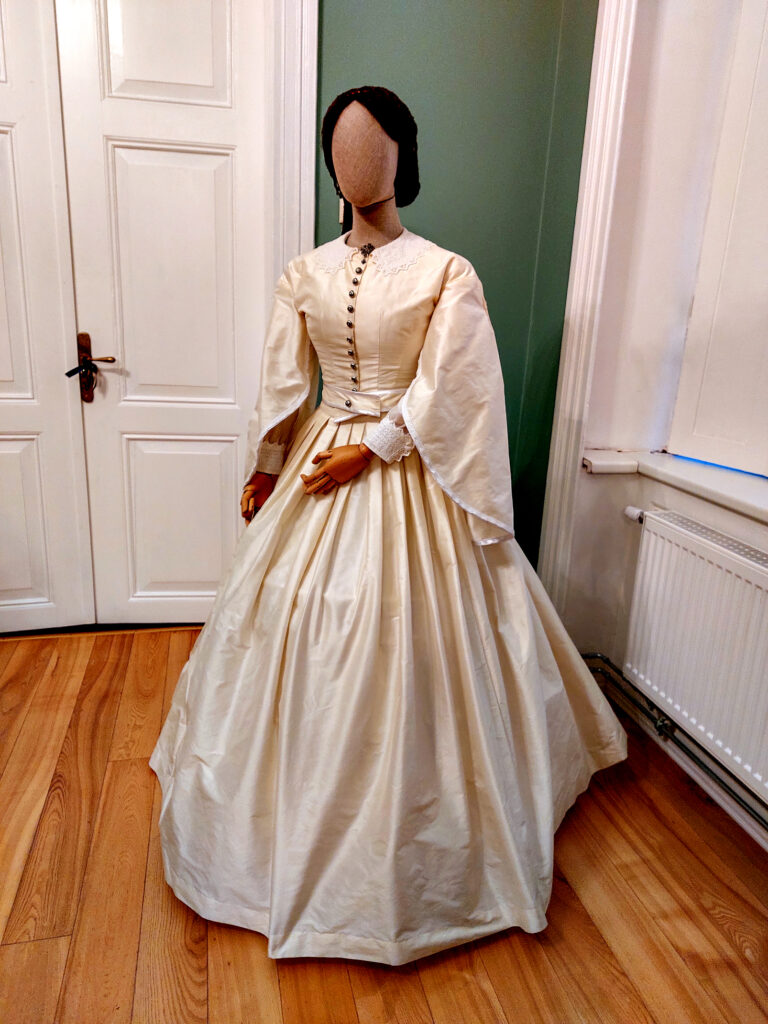 19.gadsimta kleita. “Šeit kādreiz pārvaldniece bija Zanda Zariņa, kuras aizraušanās ir vēsturisku tērpu radīšana. Tad viņa no Hānu baroneses kleitas izveidoja repliku, lai mēs varētu paskatīties, kā šī kleita varēja izskatīties,” stāsta Signe Lūsiņa.