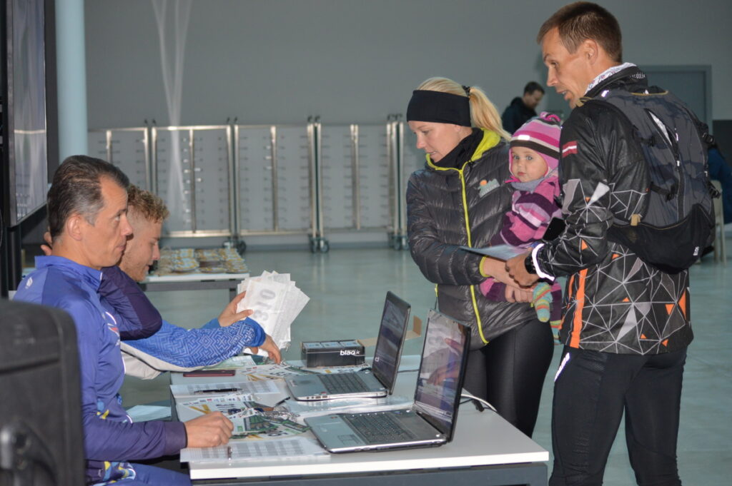 Sacensību tiesnešiem Otāram Putrālim (priekšplānā) un Ilgvaram Caunem prieks reģistrēt nakts rogaininga jaunāko dalībnieci – gadu veco Noru (attēlā kopā ar vecākiem Aivu un Uldi Kleperiem).
Autors: Foto: Sandra Pētersone