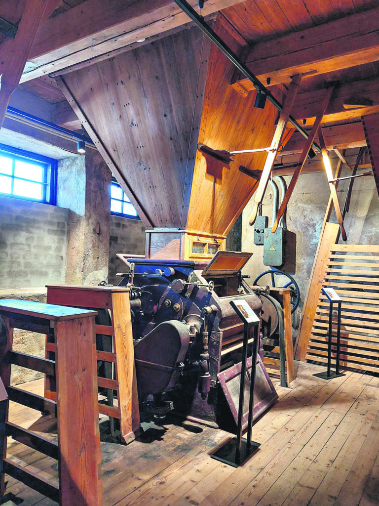 VALCIS. Graudu malšanas iekārtā ir divi pāri rotējošu metāla ruļļu.