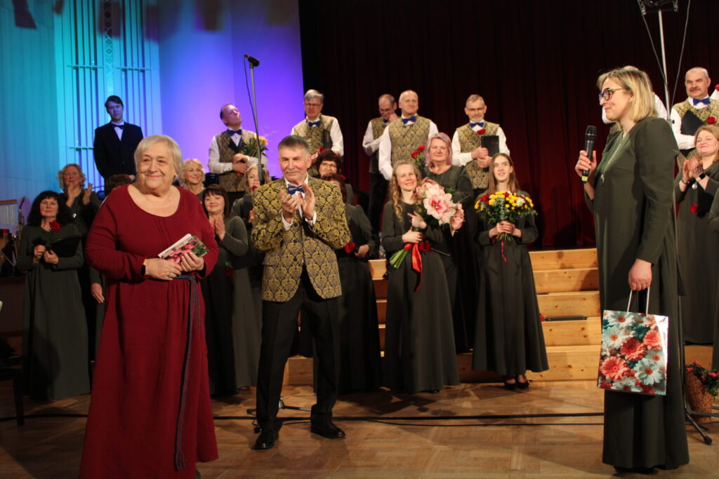 Diriģenta Ērika Deruma, kora prezidentes Ilzes Tarasas (no labās) un “Pakalnu” koristu sirsnīgu sveicienu saņēma Zaiga Krūmiņa (no kreisās) – “Pakalnu” pirmā prezidente un koriste 20 gadu garumā. Sekojot viņas pēdās, korī sāka dziedāt visa kuplā Krūmiņu ģimene.